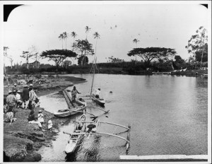 Waiakea River with fishing canoes and people gathered on shore, Hilo, Hawaii Island.